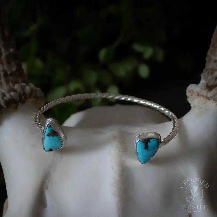 This cuff bracelet features two Carico Lake Turquoise stones set in sterling silver with a twisted cuff.